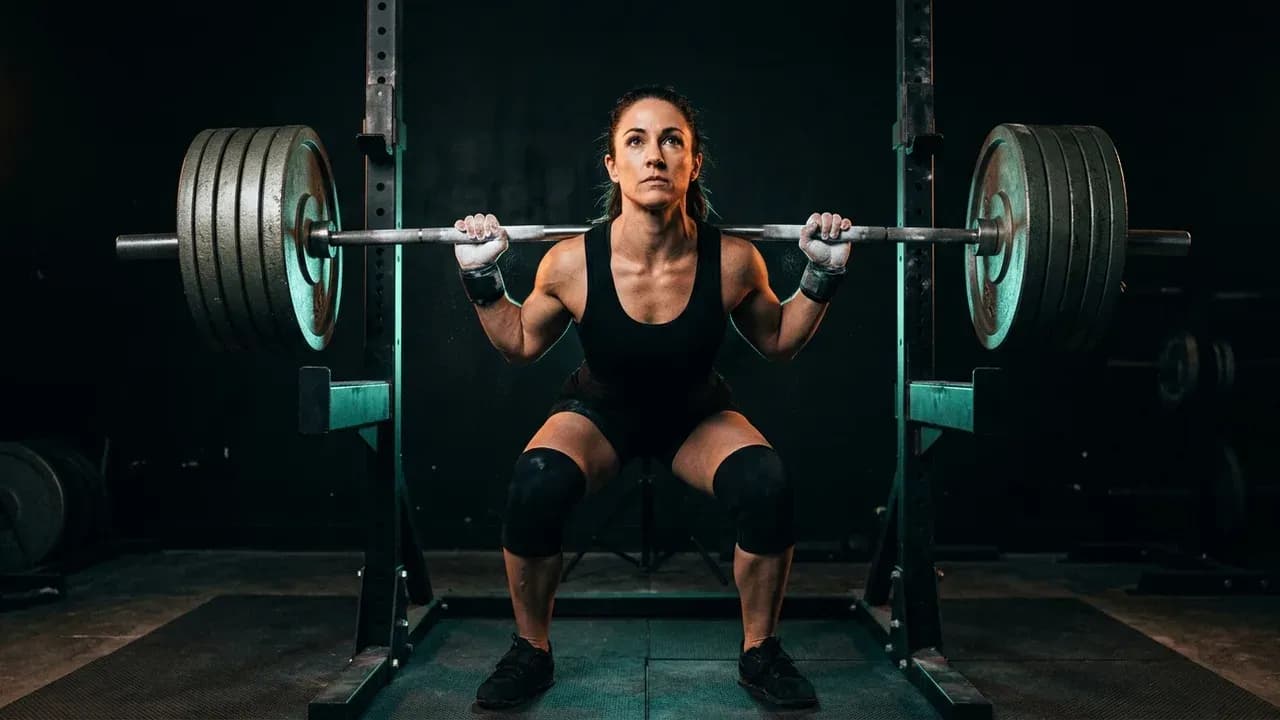 A powerlifter standing under a heavy barbell before unrack, focusing intensely with chalk on hands